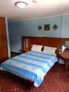 een slaapkamer met een bed met een blauw dekbed bij Hotel El Ceibo in Macuto