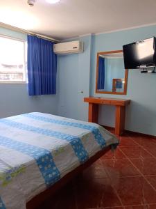 ein Schlafzimmer mit einem Bett, einem Spiegel und einem TV in der Unterkunft Hotel El Ceibo in Macuto