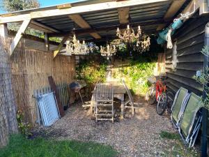 un patio con mesa y sillas bajo una pérgola en Wayside Cottage en Beaulieu