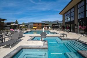 a swimming pool with chairs and a building at Luxury Amenities with a Central Location to Downtown and Whitefish Mountain Resort in Whitefish