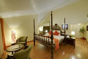 sypialnia z łóżkiem, stołem i krzesłami w obiekcie The Crown Goa w mieście Panaji