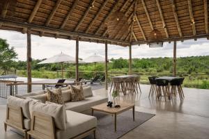sala de estar con sofá, mesas y sillas en Leopard Sands Kruger Park, en Skukuza