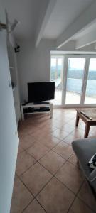 sala de estar con TV y suelo de baldosa. en La petite maison d'Hose, en Monistrol-sur-Loire