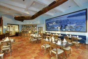 restauracja ze stołami i krzesłami oraz dużym ekranem w obiekcie The Crown Goa w mieście Panaji