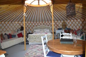 a room with a table and a couch in a yurt at The Yurt in Cornish woods a Glamping experience in Penzance