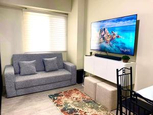 Μια τηλεόραση ή/και κέντρο ψυχαγωγίας στο 2 BEDROOM CONDO close to SM Tungko BULACAN ideal for Family Queen bed on Bedroom 1 accessible to Bedroom 2 with sliding doors Free Wifi & Netflix to watch in a comfy sofa & twin bed Access to SWIMMING POOL entry is very affordable and kids get for free