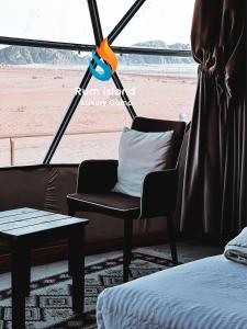a room with a chair and a bed and a table at RUM iSLAND LUXURY CAMP in Wadi Rum