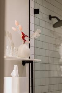 a white vase with flowers on a shelf in a bathroom at El Dorado Hotel in Sonoma