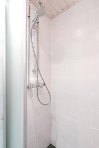 a shower in a bathroom with white tiles at City Apartment Snowberry in Rovaniemi