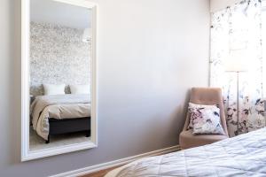 a bedroom with a mirror and a chair and a bed at City Apartment Snowberry in Rovaniemi