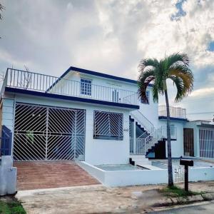 una casa blanca con una palmera delante de ella en Entire Vacation Home in San Juan - Fits 13, en San Juan