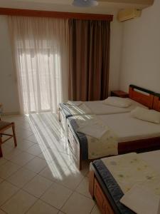 a hotel room with two beds and a window at Villa Zeus in Paralia Katerinis