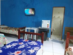 Habitación con 2 camas y TV en la pared. en POUSADA PERLLA's Pindamonhangaba, en Pindamonhangaba