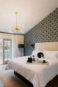 ソノマにあるEl Dorado Hotelの白い大型ベッドと壁が備わるベッドルーム1室が備わります。
