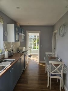 uma cozinha com armários azuis e uma mesa e cadeiras em Meadow cottage em Haverfordwest