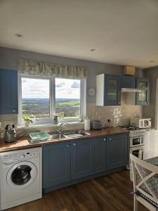 una cucina con armadi blu, lavandino e finestra di Meadow cottage a Haverfordwest