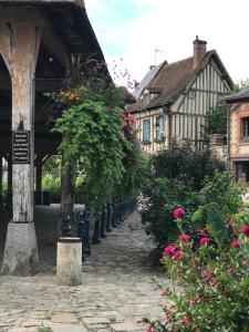 uma rua de calçada numa aldeia com casas e flores em Chambre d’hôte Lyons la foret em Lyons-la-Forêt