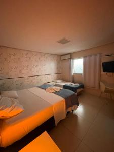 a hotel room with two beds and a window at Aldeia das Flores Hotel in Goiânia +60 photos