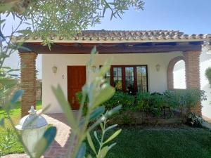 ein kleines weißes Haus mit brauner Tür in der Unterkunft Tottam Art & Healthy Garden in Málaga