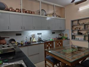 cocina con armarios blancos y mesa de cristal en Sree Nivas Homestay en Thiruvananthapuram
