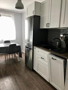 a kitchen with white cabinets and a sink and a table at Apartament na Szczecińskiej in Gdańsk