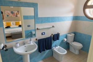ein Badezimmer mit einem Waschbecken, einem WC und einem Spiegel in der Unterkunft Sabbia & mare in Porto Torres
