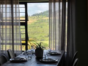 una mesa con platos y copas de vino frente a una ventana en ALOE cottage Valley of a 1000 hills en Drummond