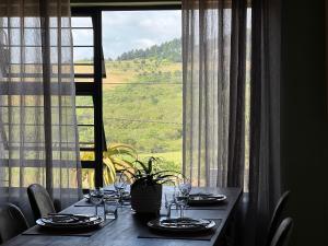 a table with plates and wine glasses in front of a window at ALOE cottage Valley of a 1000 hills in Drummond