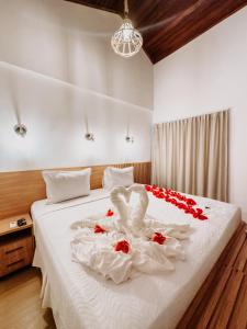 uma cama branca com um cisne feito de rosas em Pousada Luar da Ilha em Fernando de Noronha