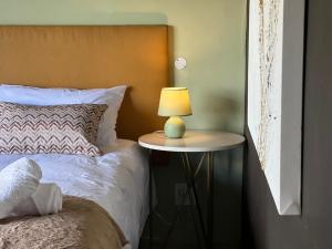 a bed with a table with a lamp on it at ALOE cottage Valley of a 1000 hills in Drummond