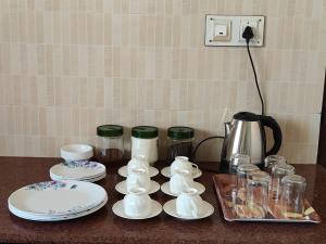 a counter with plates and cups and a coffee pot at Sunshine Villa & Homestay in Tiruchirappalli