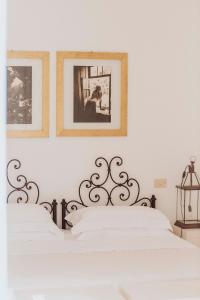 オートラントにあるMasseria Montelauroの白いベッドルーム1室(壁に2枚の写真付)