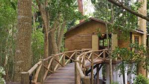 uma ponte de madeira que leva a uma cabana na floresta em Pousada Tankamana em Itaipava