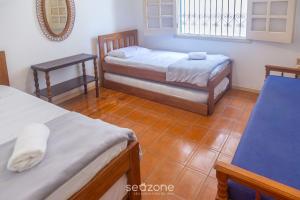 a bedroom with two beds and a mirror at Elegante Apto a 3 minutos da Praia Grande BTI003 in Ubatuba
