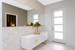 a white bathroom with a mirror and flowers on a dresser at 9312 SH - Champions Gate - Unique High end 8 Beds in Davenport +35 photos