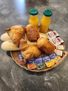 a basket of bread and pastries and bottles of orange juice at Toi et moi à 8 min d etretat in Gerville