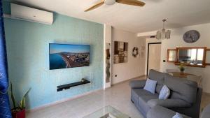 a living room with a couch and a tv on a wall at CASA EVA Naturista, Vera Playa in Playas de Vera