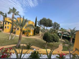 a yellow house with palm trees and a garden at CASA EVA Naturista, Vera Playa in Playas de Vera