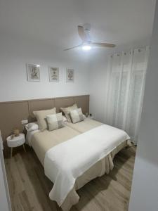 a white bedroom with a large bed and a ceiling fan at Apartamento Vitelio in Carmona