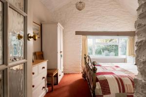 1 dormitorio con cama y ventana en Lily Pad Cottage with hot tub, en Padstow