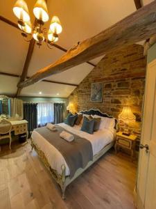 a bedroom with a large bed and a stone wall at The Grooms Cottage in Longwitton