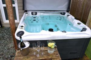 un jacuzzi con dos copas y una bebida en Luxury Pamper Home Hot Tub & Sauna Ladies Retreat en Ferndown