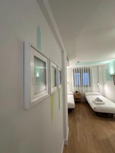 Habitación blanca con 2 camas y pinturas en la pared. en Hotel Cangas de Onis Center, en Cangas de Onís