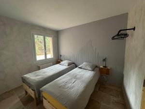 two twin beds in a room with a window at Maison au Pied de la Sainte Victoire in Puyloubier