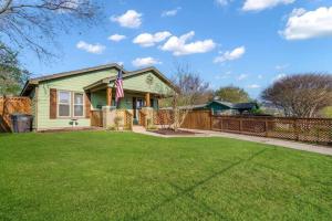 una casa verde con una bandera en un patio en Stockyards 5 mins!-New!-Sleeps 8. Cowboy Bungalow, en Fort Worth