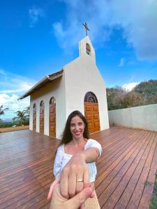 a woman sitting on a deck in front of a church at Pousada Luar da Ilha in Fernando de Noronha