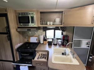 an rv kitchen with a stove and a sink at Surfside Glamping camper in Klamath