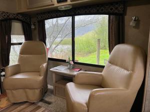 a living room with two chairs and a table and a window at Surfside Glamping camper in Klamath