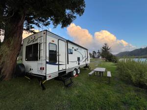 a white trailer parked next to a tree at Surfside Glamping camper in Klamath