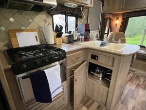 a kitchen with a stove and a sink in an rv at Surfside Glamping camper in Klamath